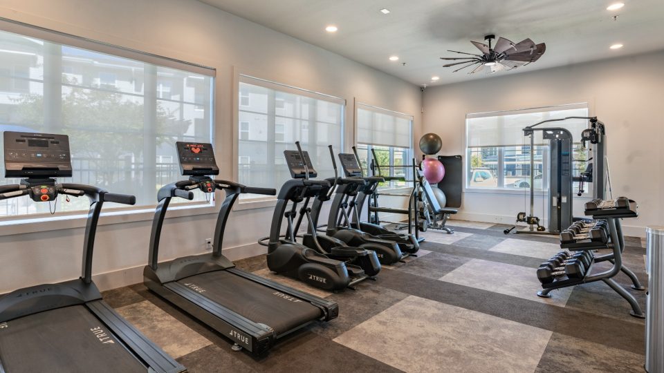a gym room with tread machines and ceiling fans at The Landmark at Crowley