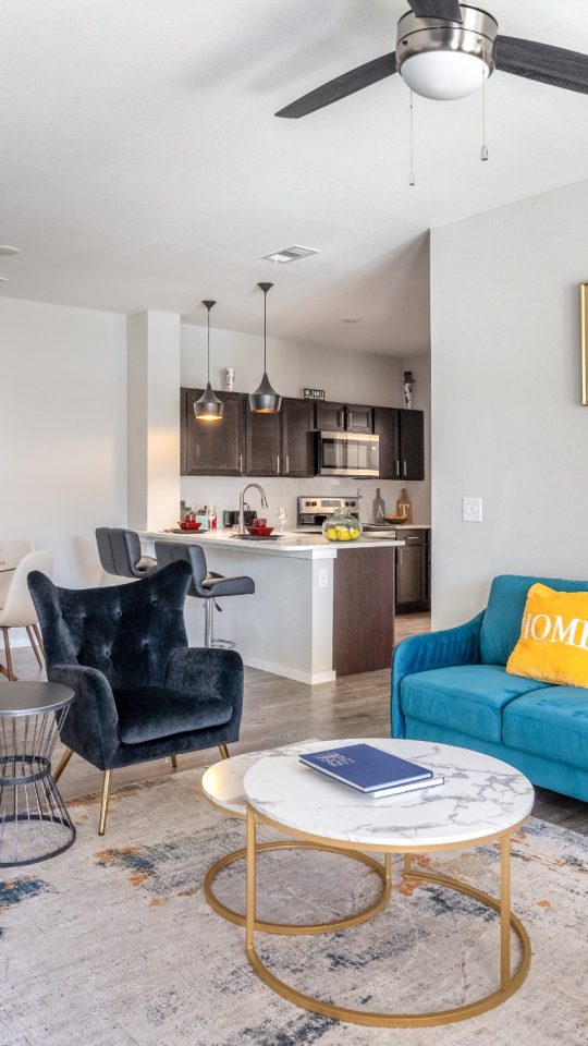 a living room with blue couches and a ceiling fan at The Landmark at Crowley