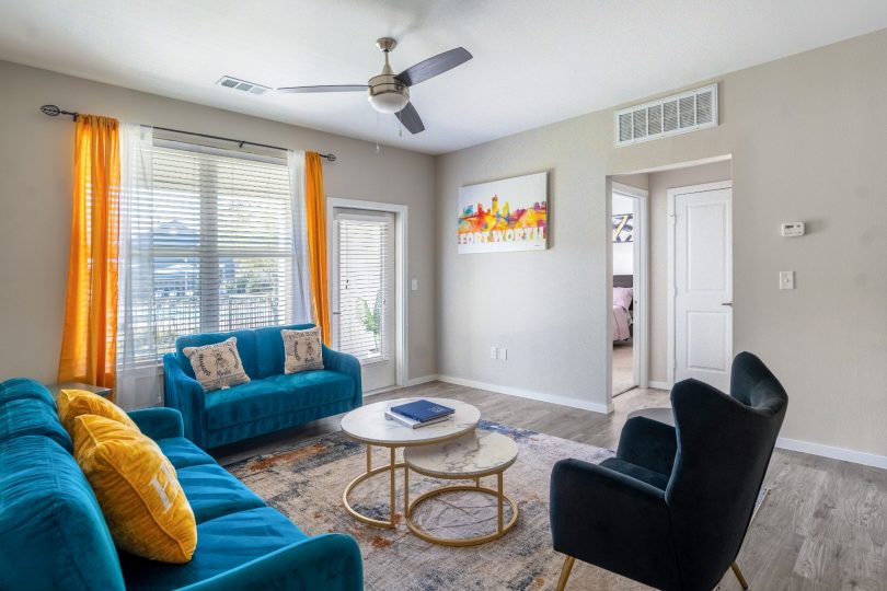 a living room with blue couches and a ceiling fan at The Landmark at Crowley