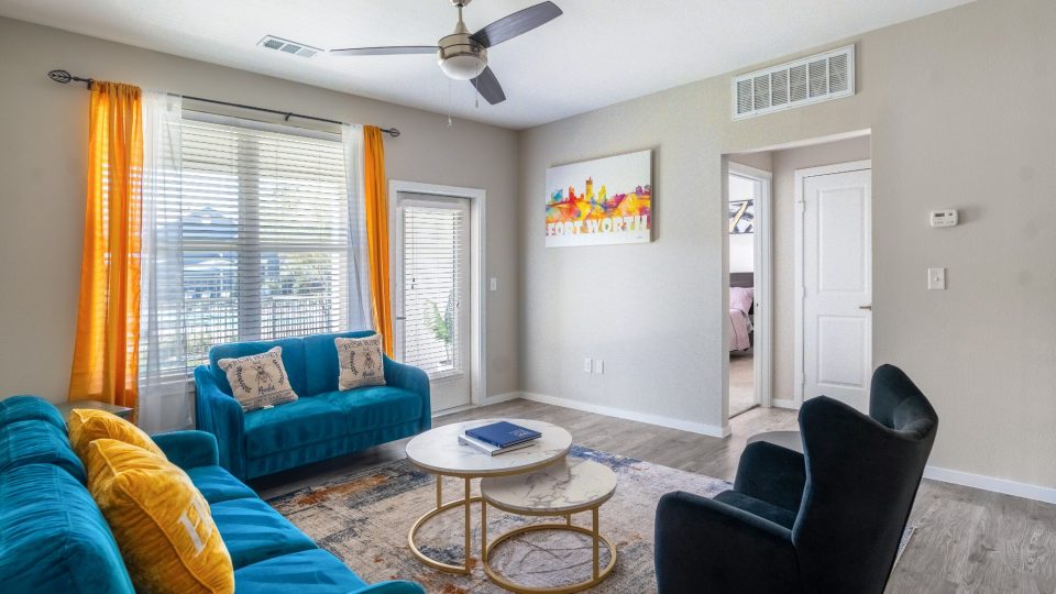 a living room with blue couches and a ceiling fan at The Landmark at Crowley